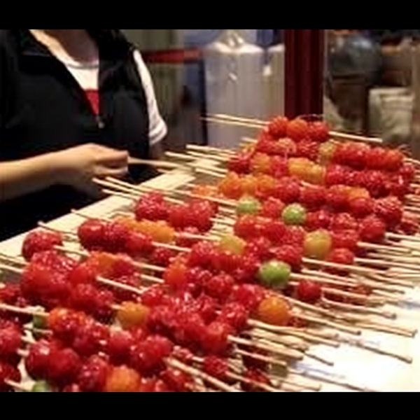 Glistening candied hawthorn berries on a stick.